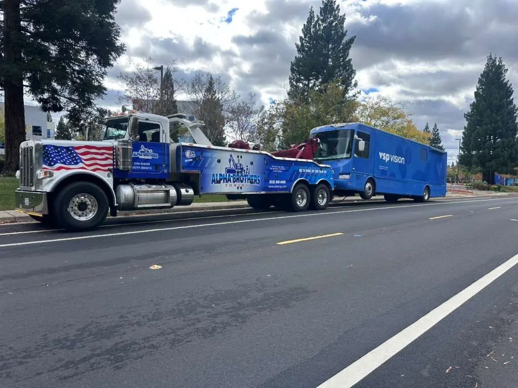 Alpha Brothers Peterbilt heavy wrecker with American flag graphics towing a VSP Vision motorhome in Sacramento, CA