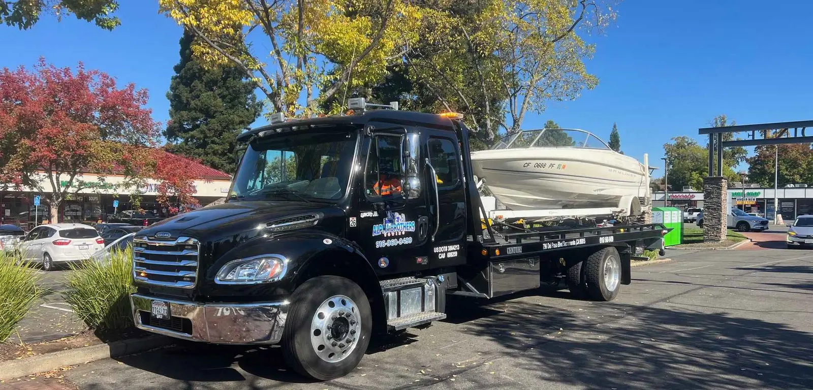 Alpha Brothers flatbed tow truck hauling a boat and trailer in Sacramento
