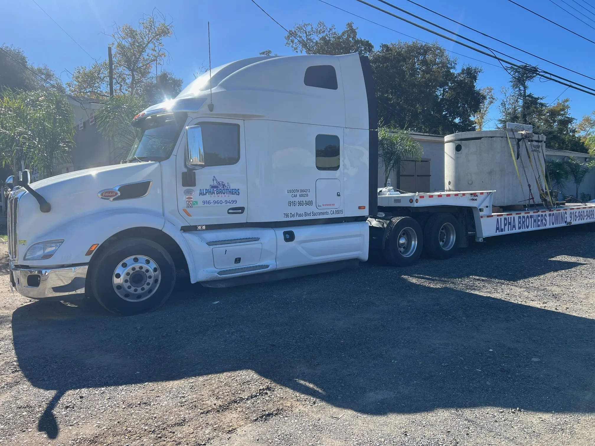 Alpha Brothers Peterbilt semi truck hauling concrete storage vaults on a flatbed trailer in Sacramento